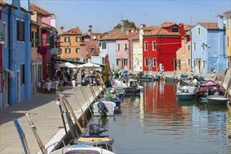 Lively place along a canal with colourful houses and terraces full of people, Burano, Venice,