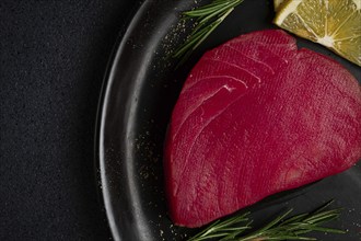 Fresh red tuna fillet, for steak, raw, top view, on a black plate, no people