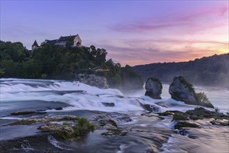 Fascinating view of a waterfall with a castle on a cliff at sunset, Schloss Laufen, Rhine Falls,