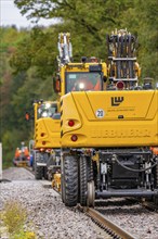 Yellow construction machinery working on a railway line in a wooded area, Hermann Hesse Bahn track