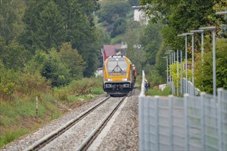 Yellow train runs through green surroundings along a railway line, track construction, rail