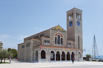 Stone church with bell tower and flags on a sunny square under a blue sky, Church of St Constantine