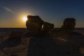 The morning sun shines through a striking rock formation in the Huqf stone desert, Arabian