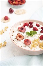 Rice flakes porridge with milk and strawberry in ceramic bowl on white concrete background and blue