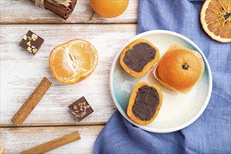 Truffle chocolate tangerine candies on a white wooden background and blue linen textile. top view,