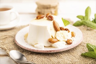 Ricotta cheese with honey and almonds on white wooden background and linen textile. side view,