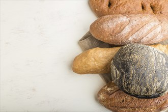 Different kinds of fresh baked bread on a white wooden background. top view, flat lay, copy space