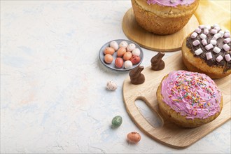 Homemade glazed and decorated easter pies with chocolate eggs and rabbits on a white concrete