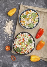 Pearl barley porridge with vegetables in blue ceramic bowls on a black concrete background and