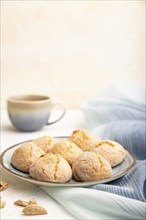 Almond cookies and a cup of coffee on a white concrete background and blue linen textile. Side