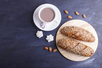 Rye bread with sunflower seeds, sesame and flax with cup of cocoa on dark blue background. top