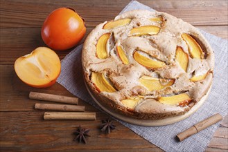 Sweet persimmon pie on brown wooden background. close up