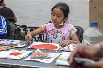 Oaxaca, Mexico, Students painting at a temporary art class in the zocalo. A girl paints a heart the