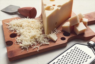 Grated cheese, Maasdam, on a cutting board, grater and cheese knife, close-up, no people