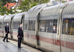 Deutsche Bahn train attendants wear face masks shortly in front of the departure of an ICE train at