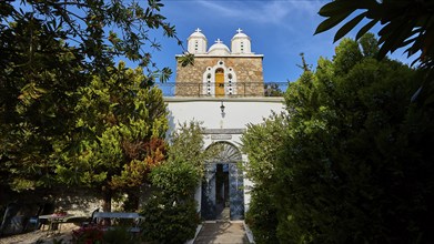 Church with white domes framed by trees and blue sky, Koroni, Byzantine fortress, nunnery,