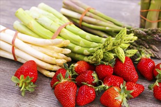 Green asparagus, white asparagus and fresh strawberries decorated on a rustic wooden table