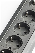 Part of a black plastic socket strip with empty sockets