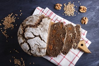 Yeast free homemade sliced bread with whole rye and wheat grains on black wooden background. close