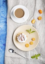 Cake with whipped egg cream on a light brown plate with kumquat slices and mint leaves on a blue