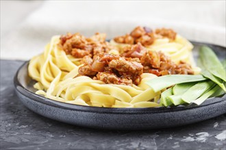 Tagliatelle bolognese pasta with minced meat on a black concrete background. side view, close up