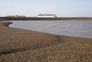 White terrace of Coastguard Cottages, beach and sea viewed from offshore, Shingle Street, Suffolk,