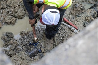 Detroit, Michigan, A new copper pipe is connected to the underground water main as workers replace