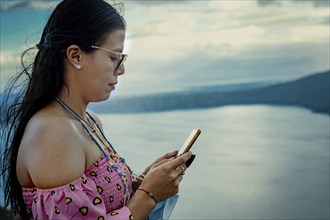 Beautiful girl in glasses checking mobile phone. Side view of young woman checking smartphone