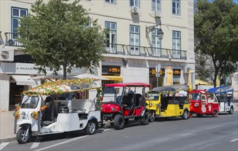 Row of colourful tuk-tuks on a city street in front of a building in sunny weather, Lisbon, Lisboa,