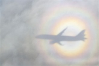 An aeroplane casts a shadow on a cloud, silhouette, halo rainbow. Germany