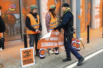 Police officer confiscates Last Generation banner after colour attack on Total Energies building.