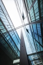 Mirrored modern glass buildings rise into the sky and reflect blue and clouds, University of