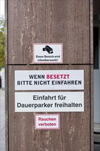 Signs with warnings about video surveillance and car park access in front of a building, no