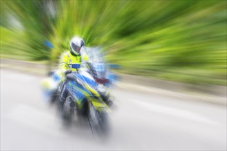 Policeman on a motorbike driving fast along the road, the speed is emphasised by the motion blur,