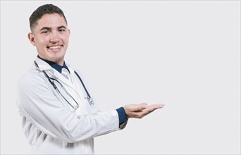 Happy doctor presenting something with his palms. Handsome doctor showing an advertisement with his