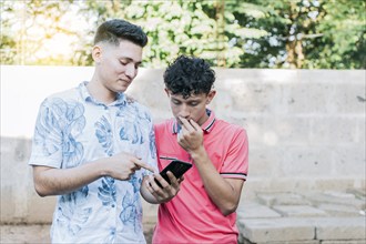 A guy showing his cell phone to another guy, Teenager explaining with his cell phone to another