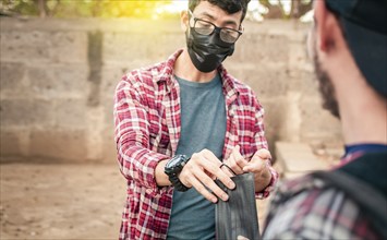 Two young people giving each other a mask, View of a young man giving a surgical mask to another