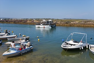 Several boats anchored in a quiet harbour basin in sunny weather, boat sailing on river Ribeiro de