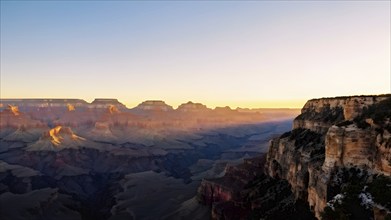 Sunrise over grand canyon in vibrant colors casting light on overhanging rock formations, AI