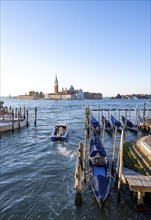 Water taxi and gondolas, San Giorgio Maggiore church in the background, evening light, Venice,