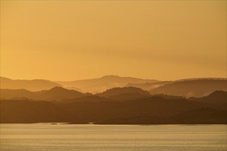 Calm atmosphere over the sea, hills and an orange sunrise, autumn, Bergen, North Sea, Norway,