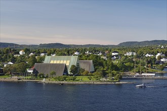 Buildings along the coast, surrounded by lush vegetation and under a clear sky, Bygdøy Museum