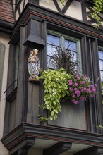 Decorative floral decoration with a statue of the Virgin Mary on a historic half-timbered house in