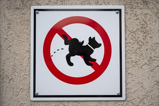 Prohibition sign on a house wall with pictogram of a urinating dog