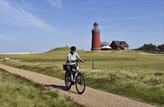 Woman, senior citizen with bicycle at the lighthouse Bovbjerg in Denmark