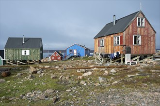 Colourful houses on rocky ground by a fjord, remote Arctic Inuit settlement Ittoqqortoormiit,