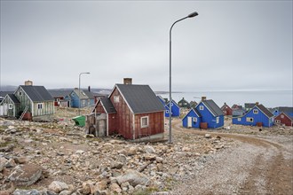 Colourful houses and gravel road with street lamps on a fjord, remote Arctic Inuit settlement