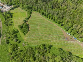 Aerial view of a solar park under construction in the middle of green fields and surrounded by