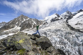 Mountaineer jumping from rock to rock, high alpine glaciated mountain landscape, La Jonction,