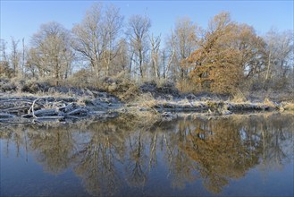 River landscape in winter, with hoarfrost, reflection on the water surface, blue sky, North